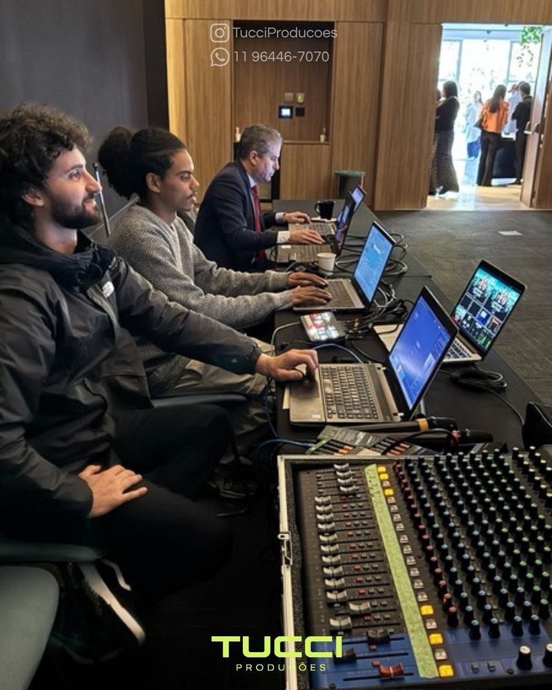 Sonorização para eventos em São Paulo: equipe técnica operando mesa de som e notebooks durante evento