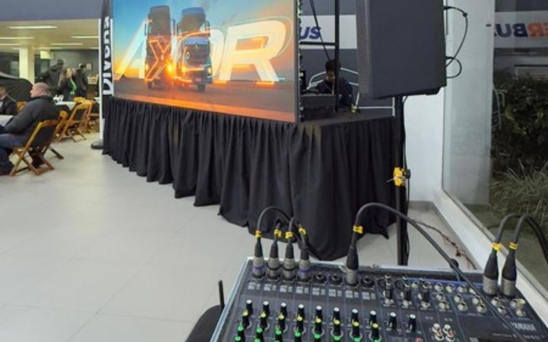 Sonorização para eventos em São Paulo: mesa de som em primeiro plano, com painel de LED e caixa de som ao fundo