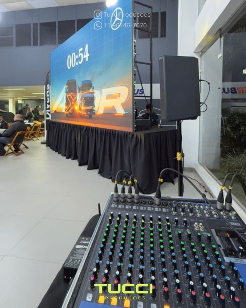 Sonorização para eventos em São Paulo: mesa de som em primeiro plano, com painel de LED e caixa de som ao fundo