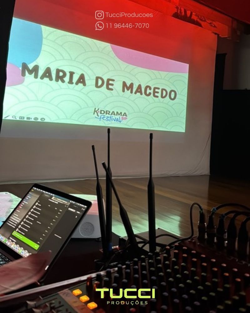 Sonorização para eventos em São Paulo: antenas de microfone sem fio ao lado da mesa de som, com o palco ao fundo