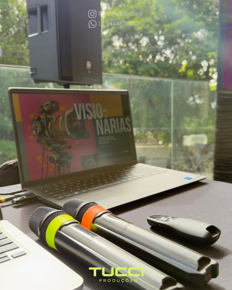 Sonorização para eventos em SP: dois microfones sem fio, notebook e passador de slides preparados para uma apresentação