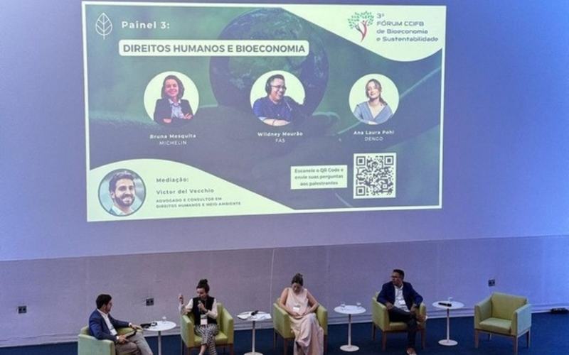 Sonorização para eventos em São Paulo: painel de debate com quatro participantes em auditório, com projeção ao fundo