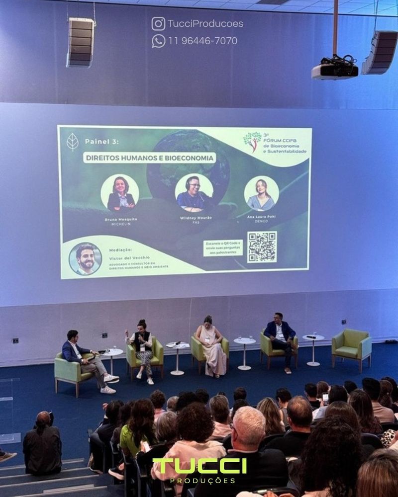 Sonorização para eventos em São Paulo: painel de debate com quatro participantes em auditório, com projeção ao fundo