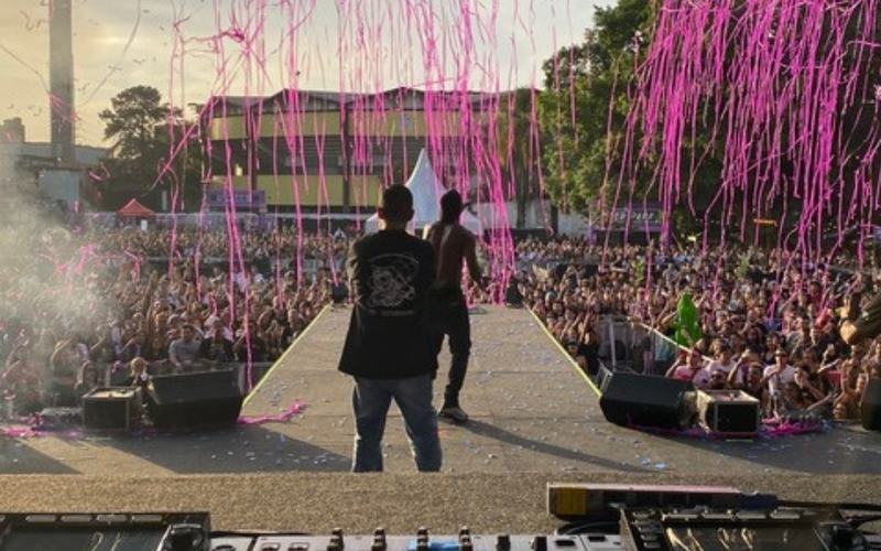 Sonorização para eventos em São Paulo: mesa de som no palco de um show ao ar livre, com caixas de som e público